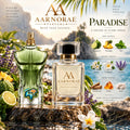 A clear glass perfume bottle with a black cap and gold collar sits on a stone surface in a tropical outdoor setting. The bottle is labeled AARNORAE PARFUMS and reads 'WEAR YOUR ESSENCE.